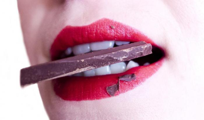 девушка держит шоколадку в зубах